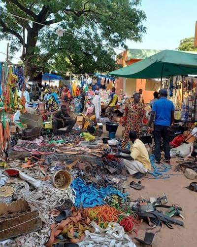 Puesto de cuerdas, sandalias y objetos cotidianos bajo un árbol
